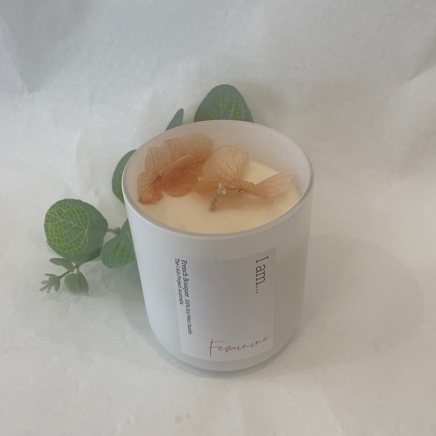 Candle in a white container with decorative elements on a light background