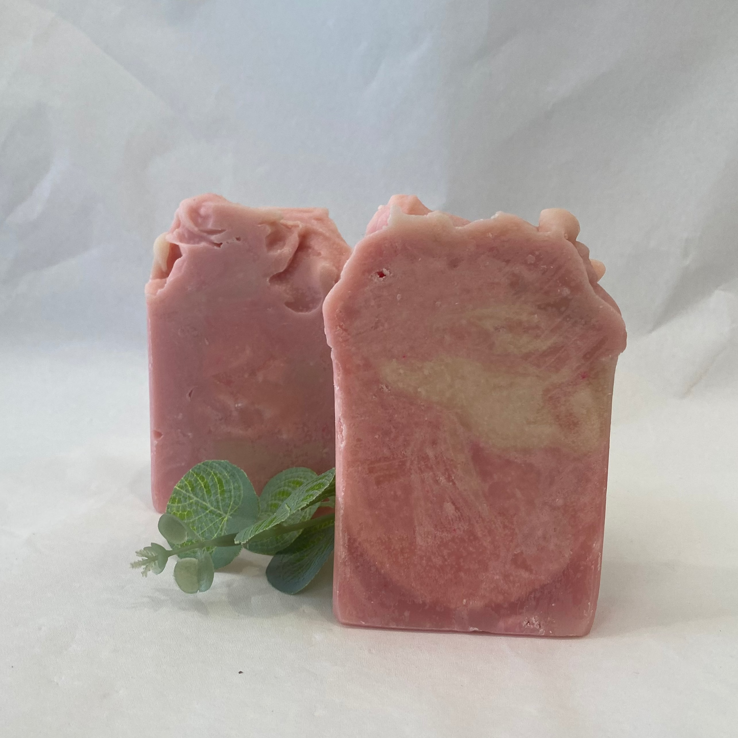 Two pink soap bars with a green leaf on a white background