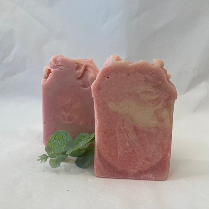Two pink soap bars with a green leaf on a white background
