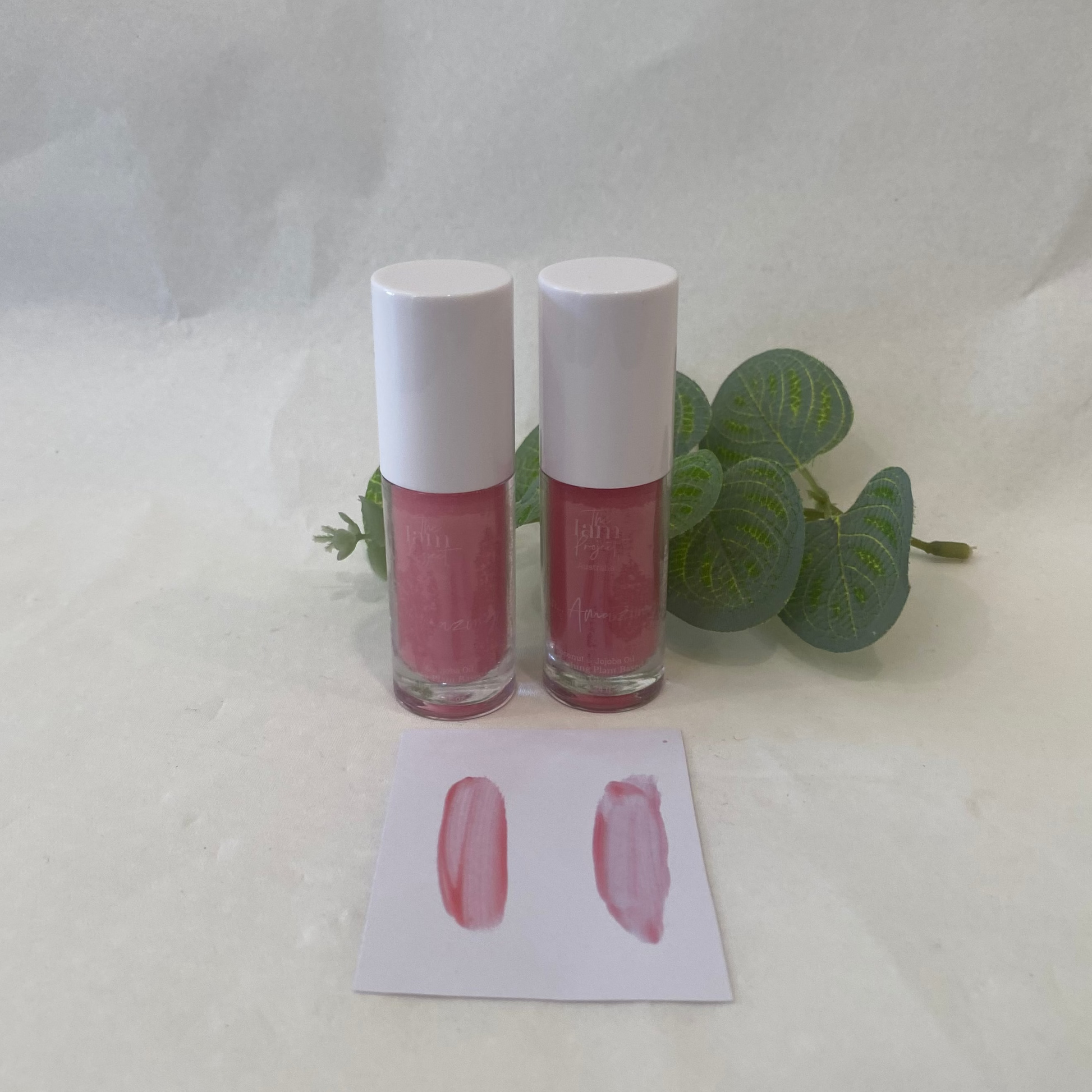 Two lip gloss bottles with a swatch on a white background