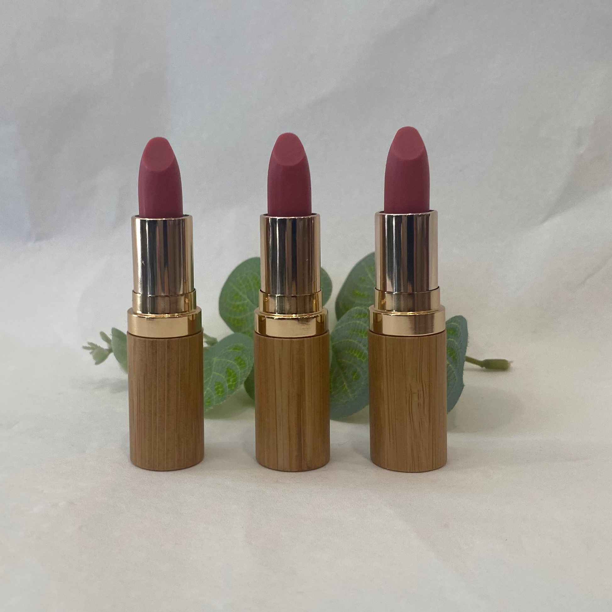 Three lipsticks with gold casings on a white background