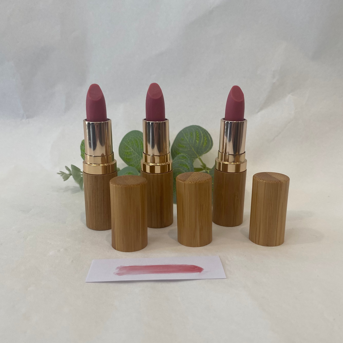 Set of three lipsticks with wooden casings on a white background