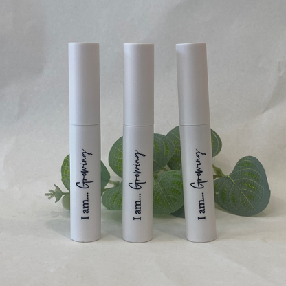 Three white Eyelash Serum bottles with text on a light background