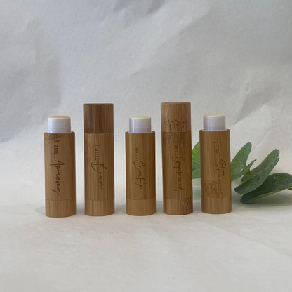 Set of five wooden lip balm containers with white caps on a light background