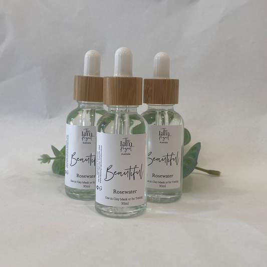 Three glass dropper bottles with wooden caps on a white background