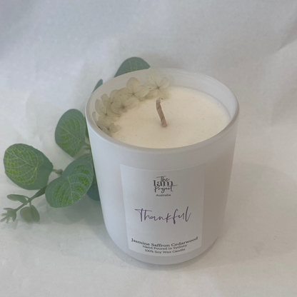 White candle in a glass jar with a label on a white background