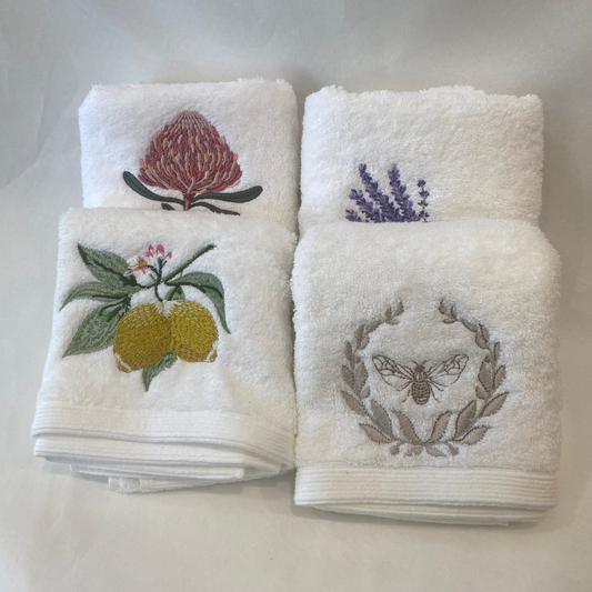 Set of four white towels with embroidered designs on a white background
