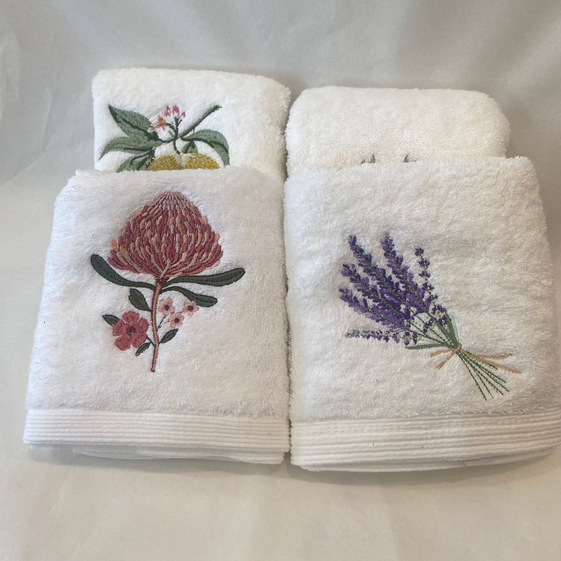 Set of white towels with floral embroidery on a white background