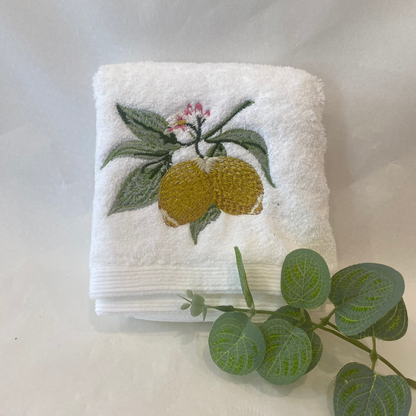 White towel with embroidered lemons and leaves on a white background