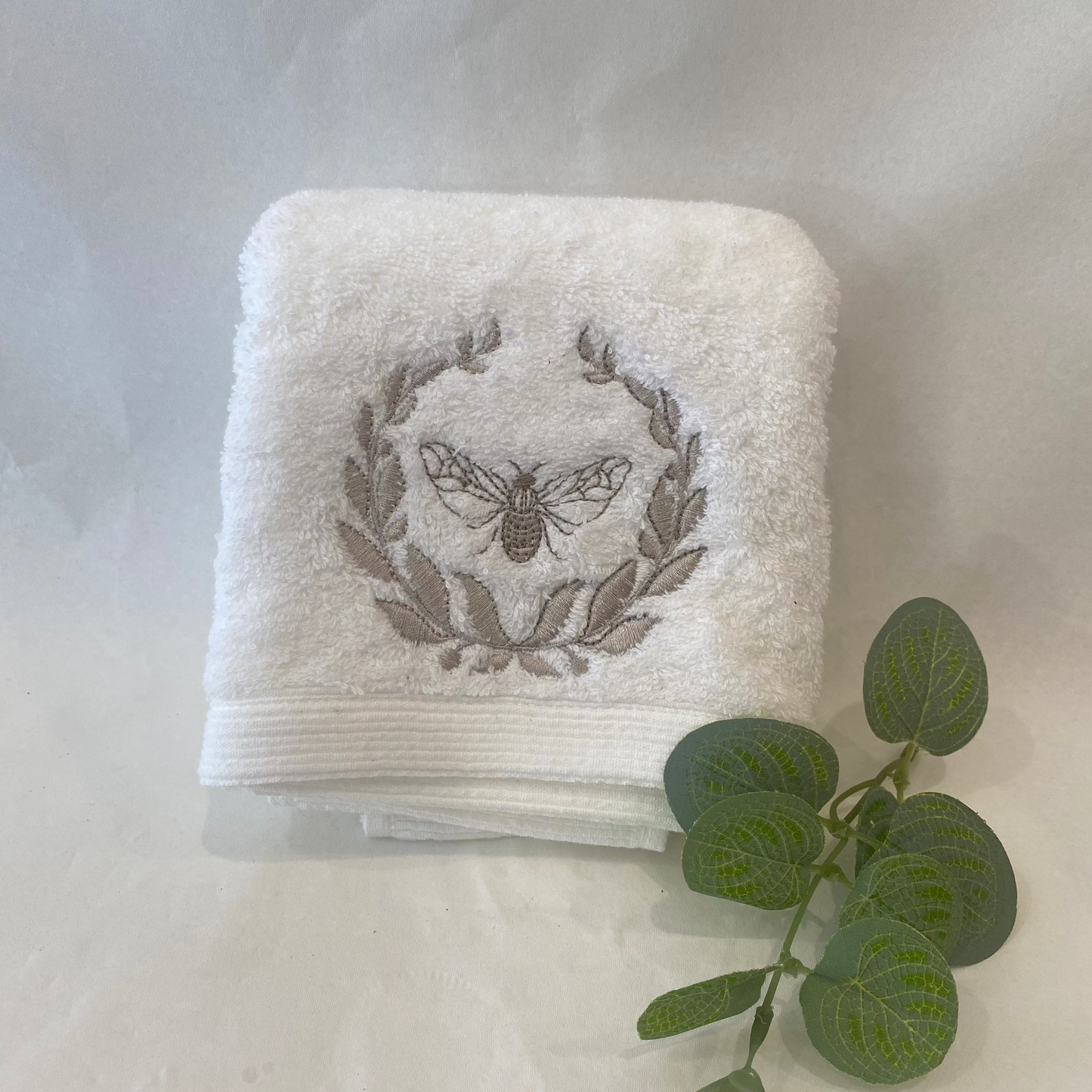 White towel with embroidered design on a light gray background