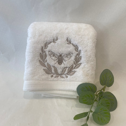 White towel with embroidered design on a light gray background